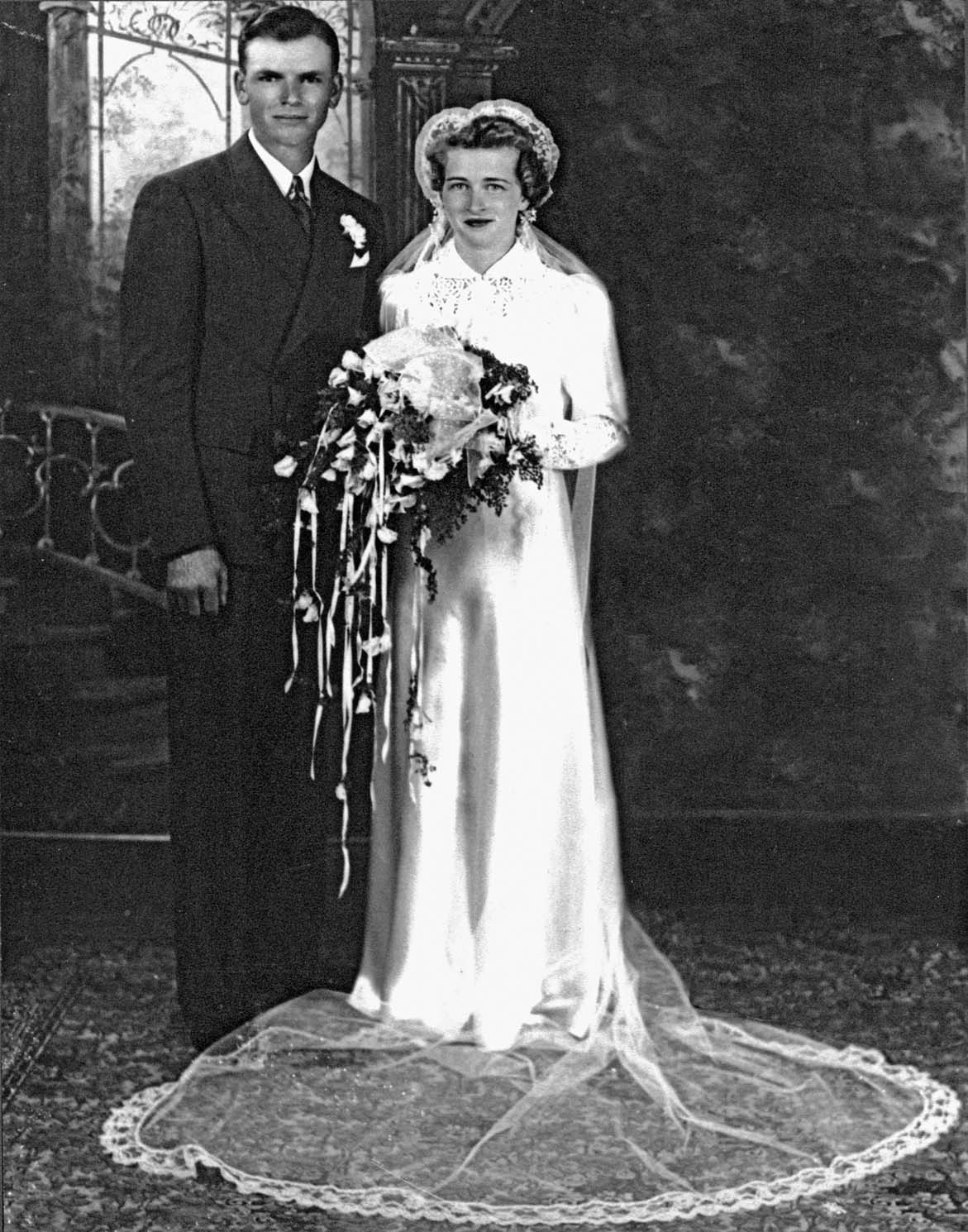 A young man and woman pose in their wedding dress and suit