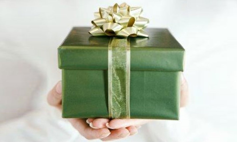 Green gift box with gold bow on top and ribbon around it