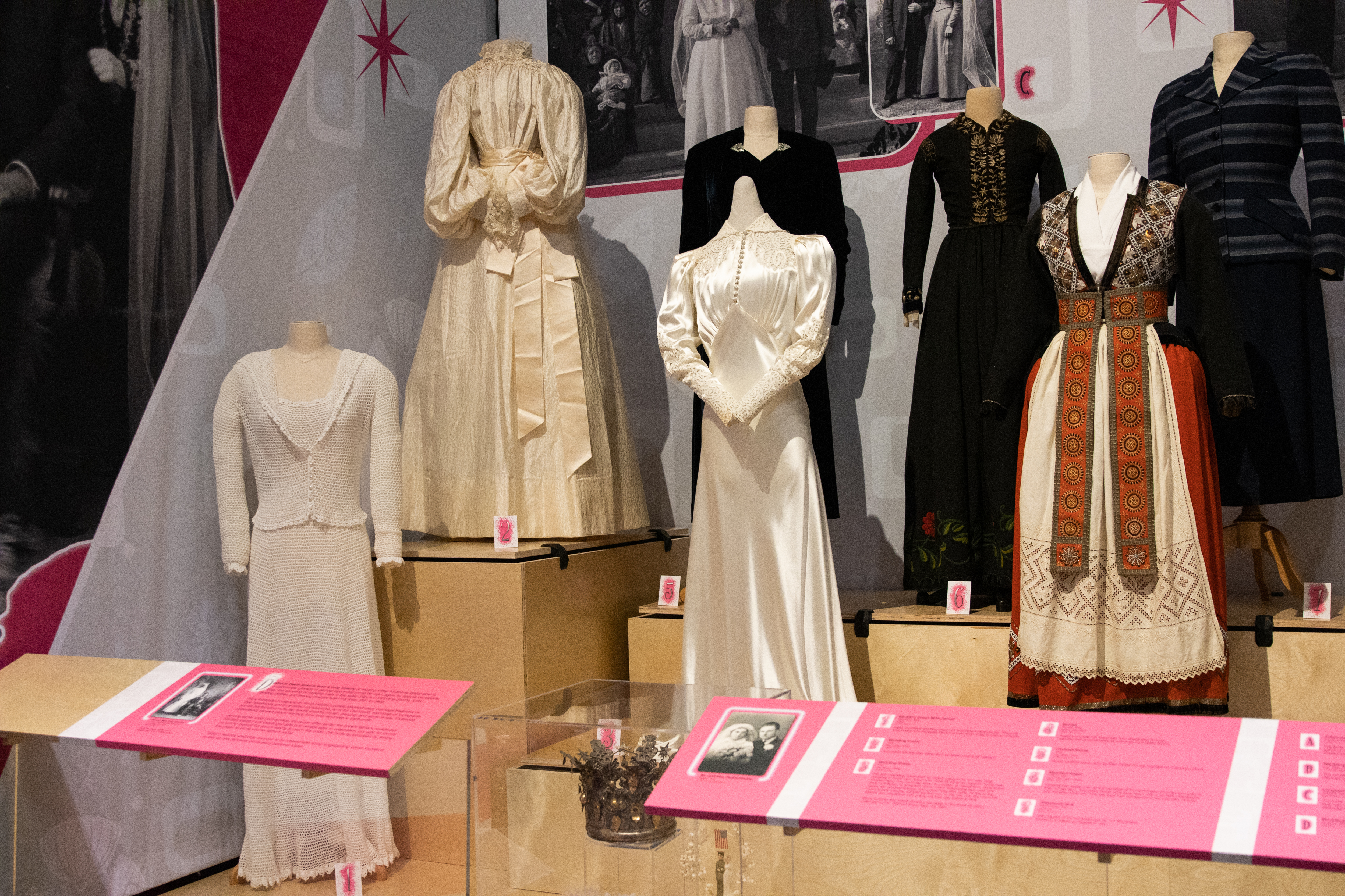 Many mannequins are dressed in different old wedding gowns for a museum display